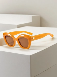 Detailed view of orange cat-eye sunglasses with gold metal hinge and brown lenses