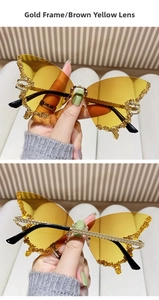 Close-up of butterfly rimless sunglasses with gold crystal rhinestones and yellow lenses