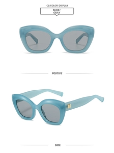 Detail view of light blue cat eye sunglasses with gray lenses and gold square metal accents
