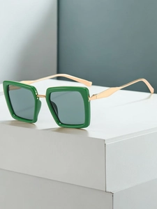 Detail of square dark green sunglasses with gold metal temples on geometric props