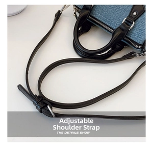 Detail view of denim pillow bag showing black leather handle and adjustable strap with silver rings