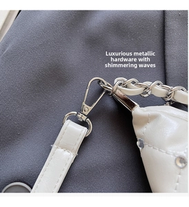 Gros plan sur les crochets argentés et strass de ce sac à bandoulière matelassé blanc