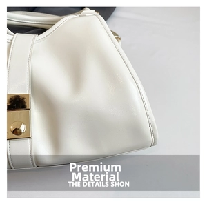 Détail d'un sac à main blanc en cuir texturé avec boucle métallique dorée polie