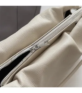 Detailed macro of smooth silver zipper and lychee pattern leather on beige cloud bag