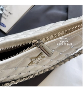 Détail du zip argenté et du pendentif étoile sur un sac à main blanc matelassé chic