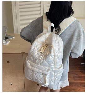 Close-up of white quilted puffer backpack with heart patterns and glossy finish