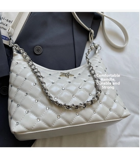 Détail du sac matelassé blanc avec strass, ornement étoile dorée et chaîne métal