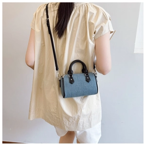 Rear view of a model wearing the mini navy denim Boston bag with black leather straps