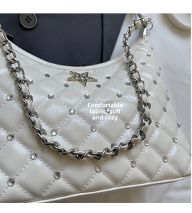 Détail du sac à main blanc matelassé avec strass brillants et boucle étoile dorée