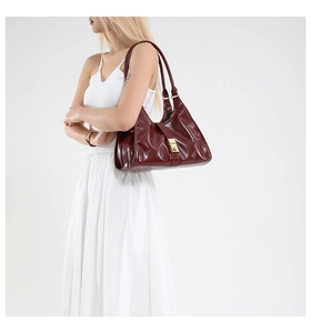 Détail d'un sac à main en cuir verni bordeaux avec boucle dorée et doubles anses élégantes