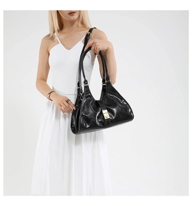 Détail du sac sous le bras en cuir noir brillant avec fermoir doré et bandoulière