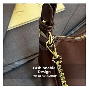 Macro shot of dark brown leather crescent bag with polished gold hardware and chain detail