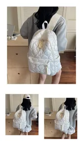 Detail view of white quilted puffer backpack showing heart patterns and woven zipper pulls