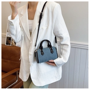 Close-up of mini denim boston bag with black leather handles and adjustable shoulder strap