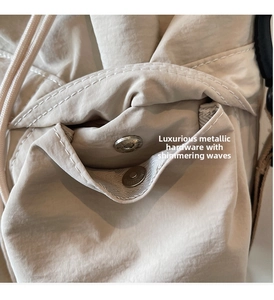 Detail of cream nylon bag featuring silver magnetic buckle and woven drawstring