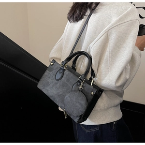 Vue détaillée d'un sac à main gris foncé minimaliste avec poignées cuir et détails dorés
