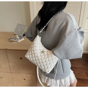 Détail d'un sac à main matelassé blanc avec rivets argentés et ornement étoile sur chaîne