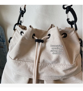 Detail of beige bucket bag with drawstring closure and durable climbing hook hardware
