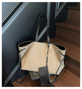 Detail of khaki canvas tote bag with black leather straps and matching card holder pouch