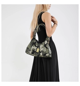 Détail d'un sac à bandoulière camouflage avec boucle dorée porté par un mannequin