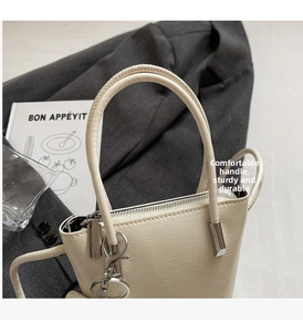 Detail of off-white bucket bag with pleated texture, silver hardware and round handle
