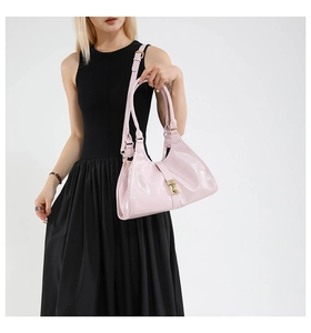 Detail of a pink glossy patent leather handbag featuring a golden square twist lock buckle