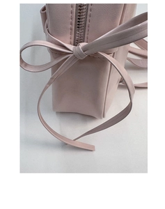 Close-up of light pink PU leather bag featuring a decorative side bow and smooth zipper