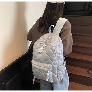 Detail of silver heart-quilted space cotton backpack with woven zipper pulls and side pockets