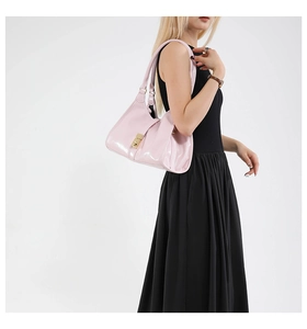 Détail du sac sous le bras en cuir verni rose clair avec un fermoir carré doré brillant