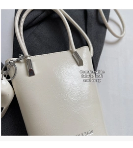 Detail showing the off-white glossy wrinkled leather texture and silver metal hardware of the bag