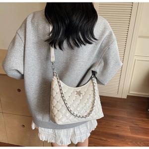Détail du sac à bandoulière beige matelassé avec logo étoile et chaîne sur un mannequin