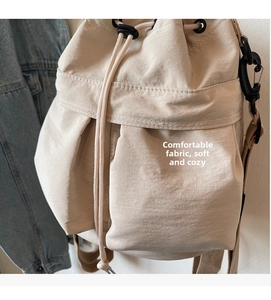 Detail of beige nylon drawstring bucket bag with side pocket and metal hook