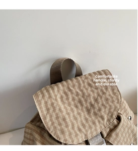 Nahaufnahme des braun karierten Rucksacks mit Tragegriff und Klappen-Details