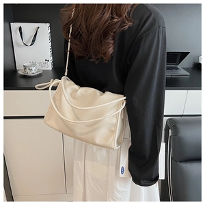 Détail du sac en cuir crème souple avec bandoulière nouée et design plissé élégant