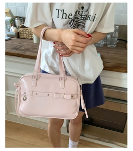 Detail of pink faux leather handbag with ribbon bow and silver heart charm decoration