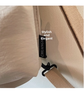 Close-up of beige fabric shoulder bag with CHUANGM woven label and black plastic buckle