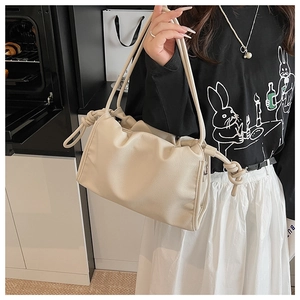 Détail du sac à bandoulière en cuir beige texturé avec nœud décoratif et design souple cloud