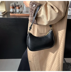 Close-up of black leather hobo bag with gold hardware worn with a classic khaki coat