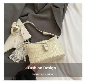 Détail du sac seau tissé crème avec pendentif en dentelle perlée et boucle argentée