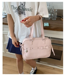 Detail of pink JK style handbag featuring a sweet bow and silver heart pendant