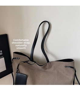Detail of tan suede tote bag with black straps, silver rivets, and decorative mini card pouch