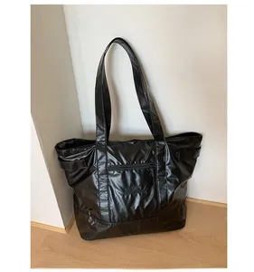 Gros plan d'un grand sac cabas noir en tissu brillant avec poche avant zippée