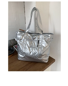 Détail d'un grand sac fourre-tout argenté montrant la texture et la broderie grise