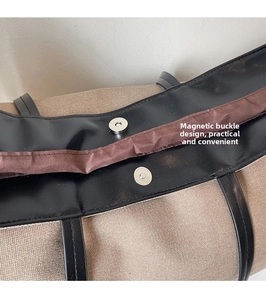 Detail of canvas tote bag showing silver magnetic closure and leather trim texture