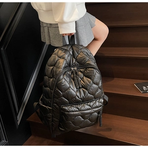Detail of quilted black puffer backpack with woven zipper and glossy nylon texture