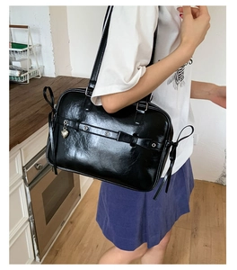 Side view of a large black glossy PU leather tote bag with heart charm and bow details