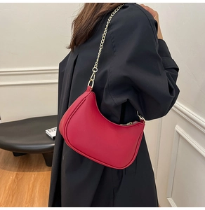 Close-up of a stylish red crescent shoulder bag with elegant gold chain strap and zipper
