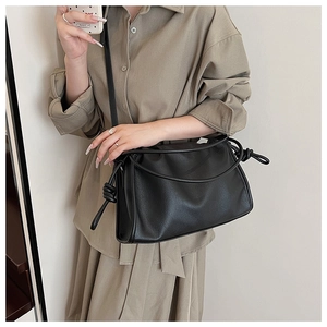 Détail du sac à bandoulière en cuir noir avec nœuds décoratifs sur la sangle