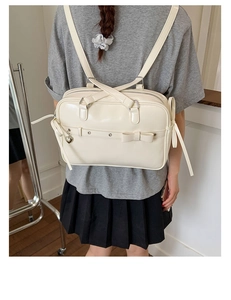 Fashionable cream white bow backpack worn by a model in a trendy school-style outfit
