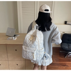 Close-up of white quilted puffer backpack with diamond stitching and shiny nylon material